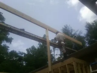 Carpenter setting a ridge beam over a new addition frame — Ice Dam Removal by Roofing Brothers in Little Cedar