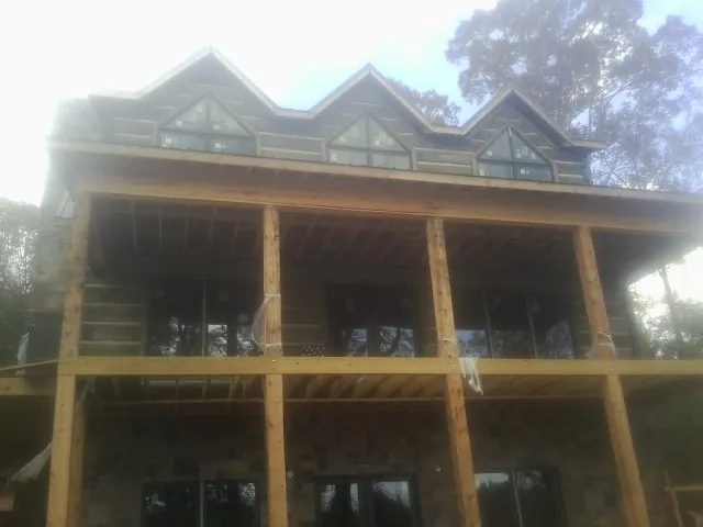 Dormers and porch framing on a large log home under construction — Roof Coating work by our crew in Little Cedar