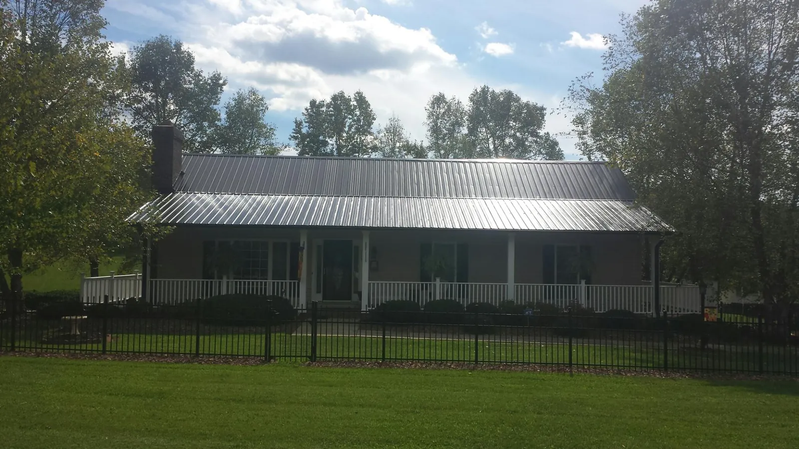 Gray metal roof on a brick ranch with a full width front porch — Gutter Guard Installation work by our crew in Little Cedar