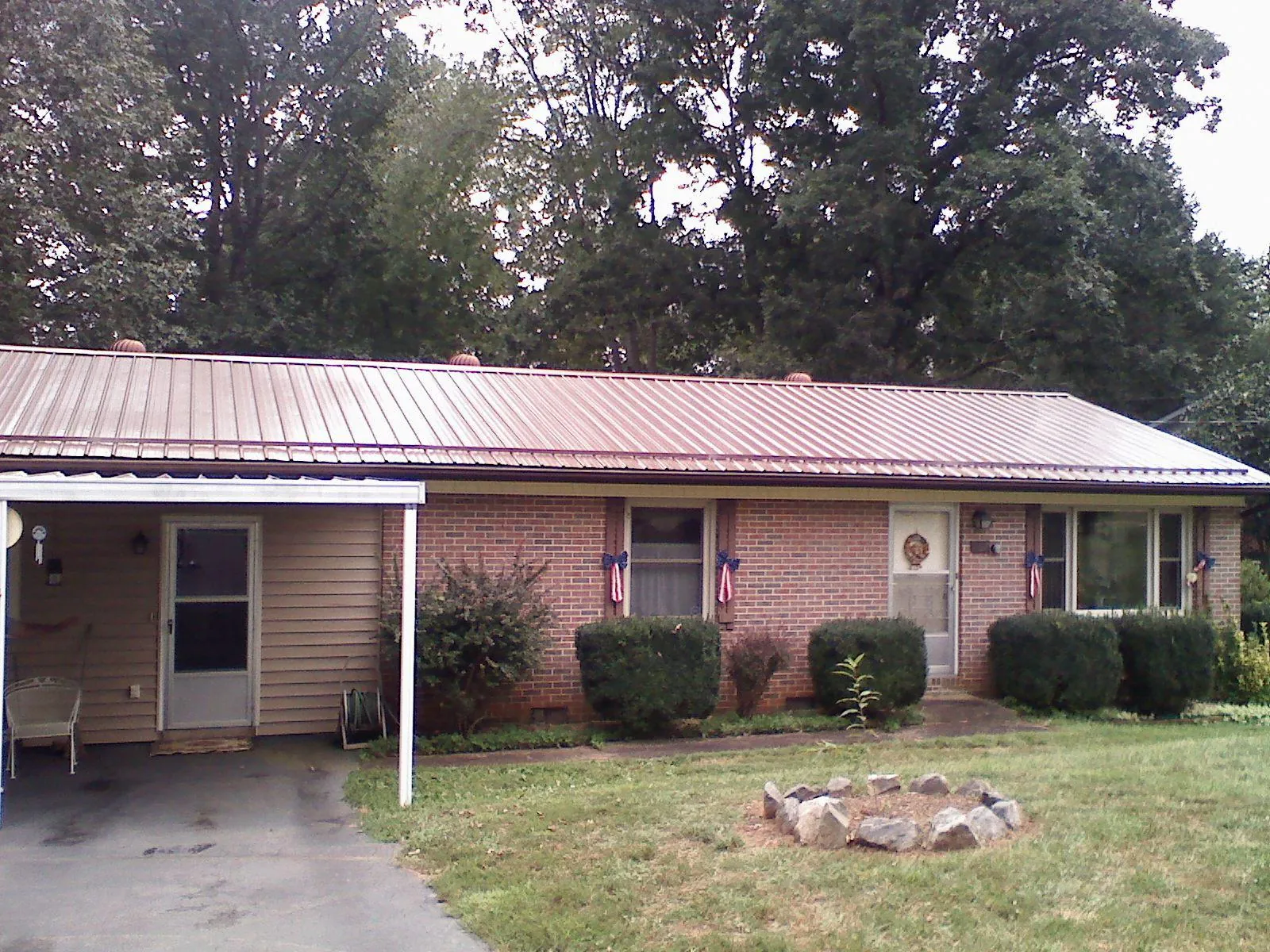 Bronze metal roof and carport on a brick ranch home — Roof Repair work by our crew in Little Cedar
