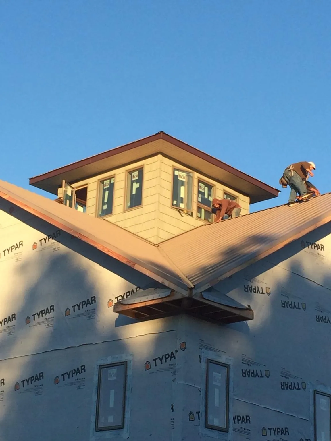 Roofers working around a rooftop cupola on a new metal roof at sunset — Roof Waterproofing in Little Cedar by Roofing Brothers
